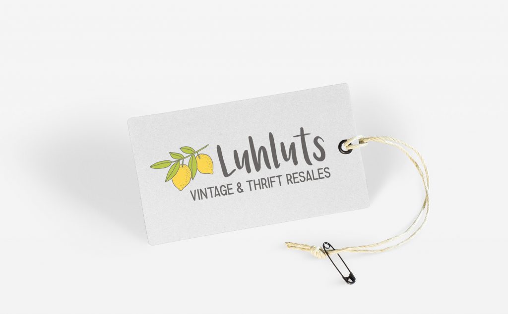 a card, on a string with a safety pin, on the card is a printed logo containing a cluster of lemons and the words Luhluts vintage & thrift resales